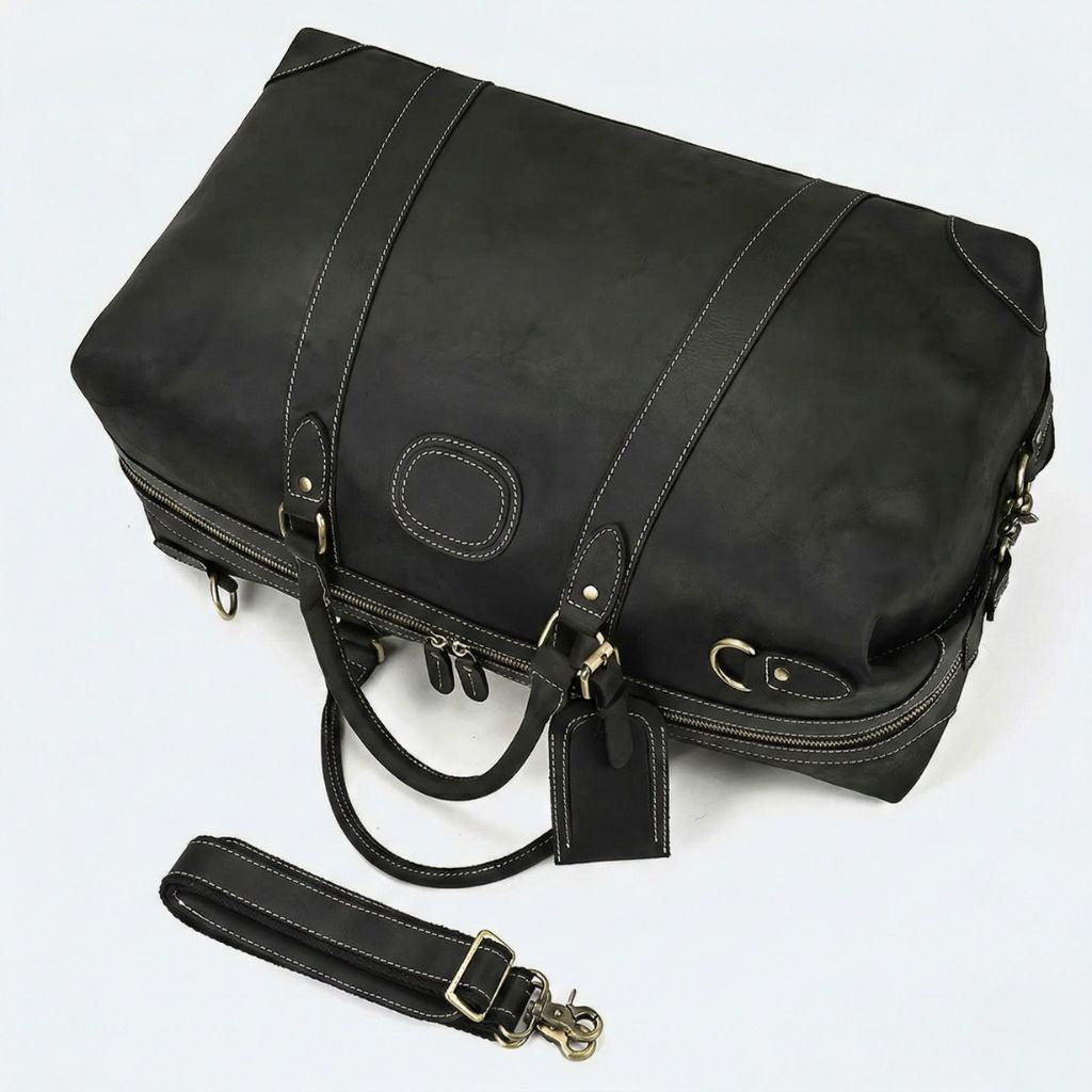 Vue plongeante du sac noir mat, double fermeture zippée sur le dessus et bandoulière cuir détachée posée