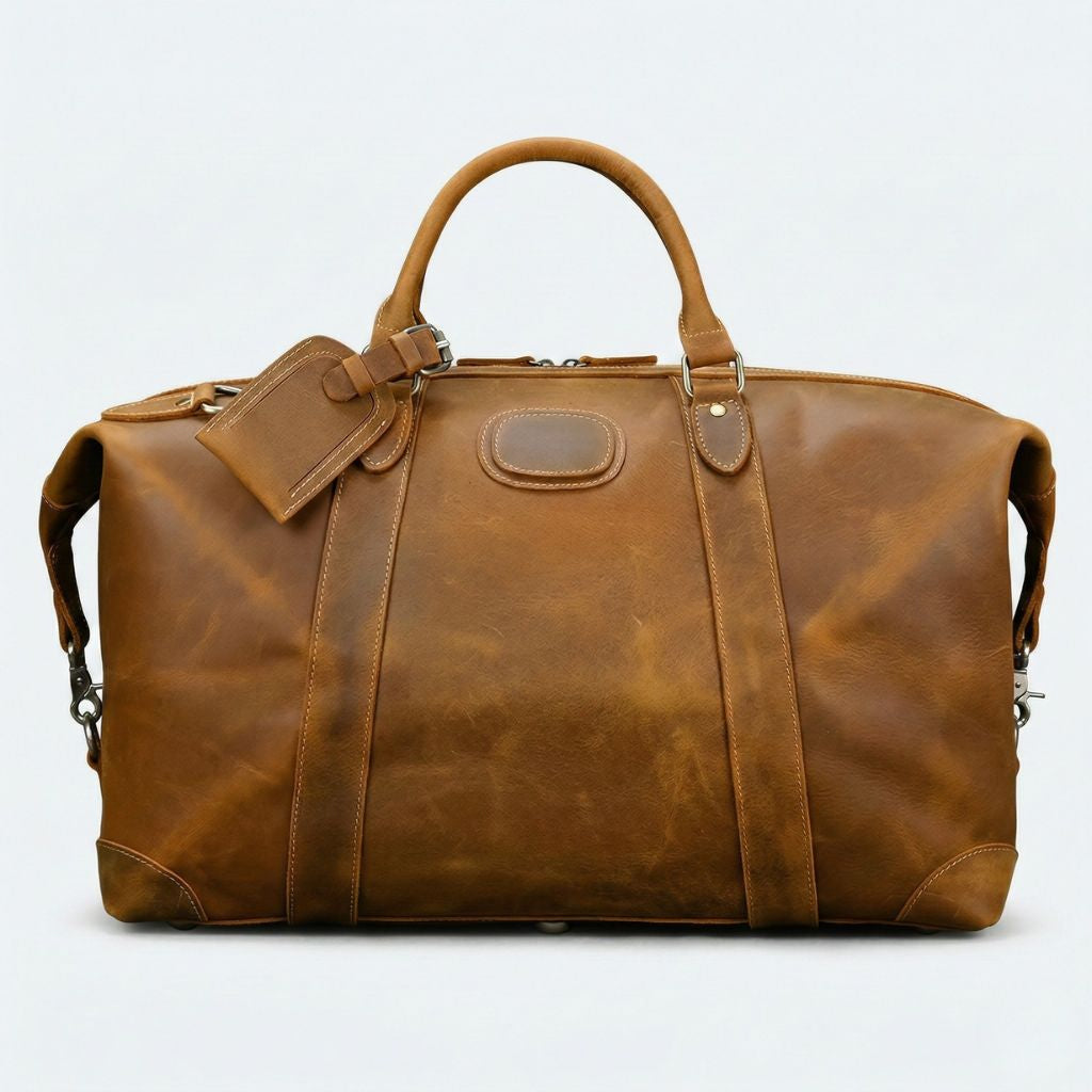 Face avant du sac de voyage cuir cognac clair, panneau central renforcé, étiquette et plaque ovale cousue