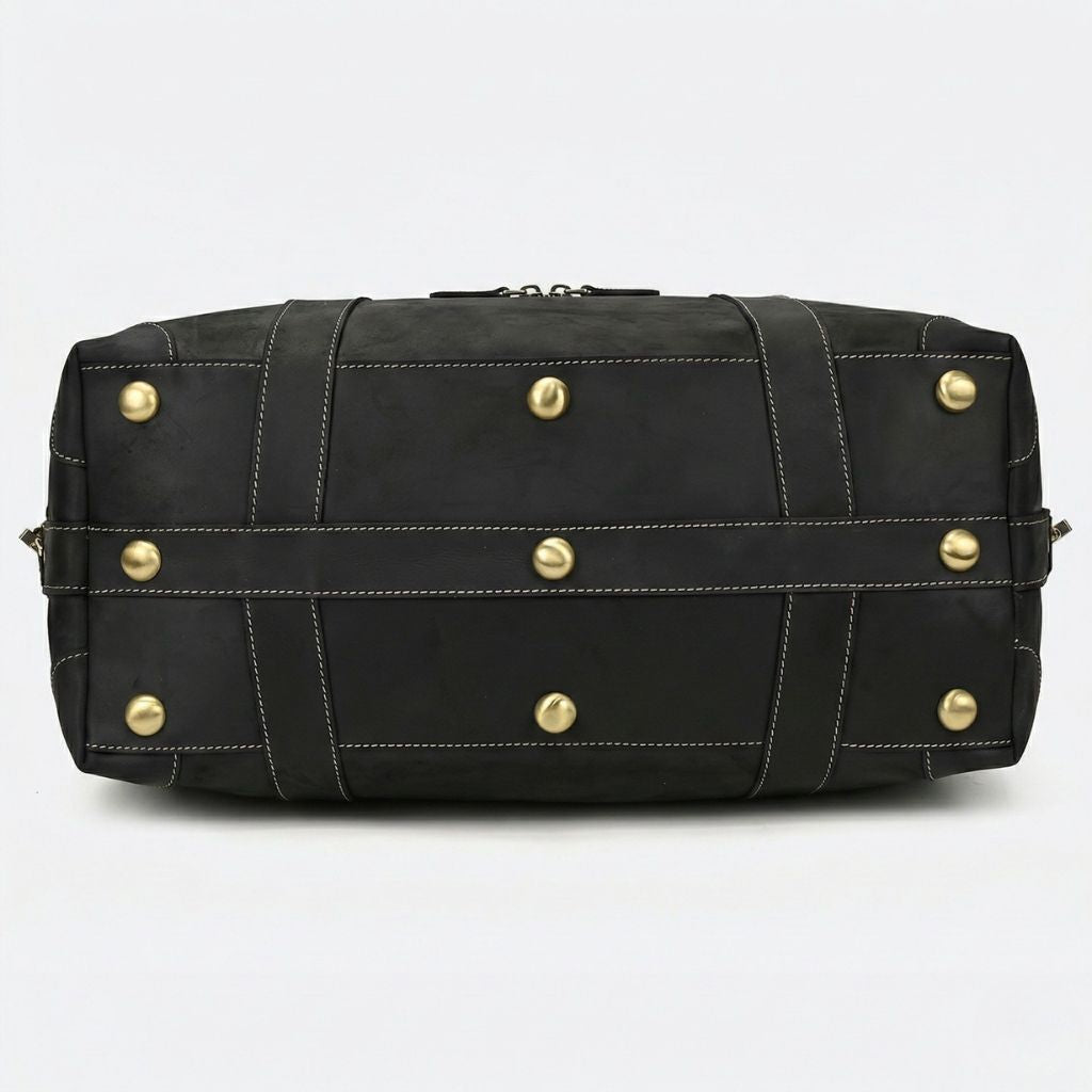 Fond du sac de voyage en cuir noir mat, huit pieds protecteurs en laiton doré et sangles entrecroisant