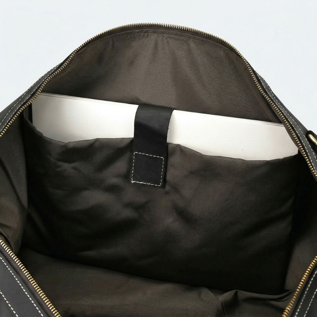 Vue intérieure du compartiment noir mat, poche ordinateur avec languette cuir noire et laptop blanc glissé