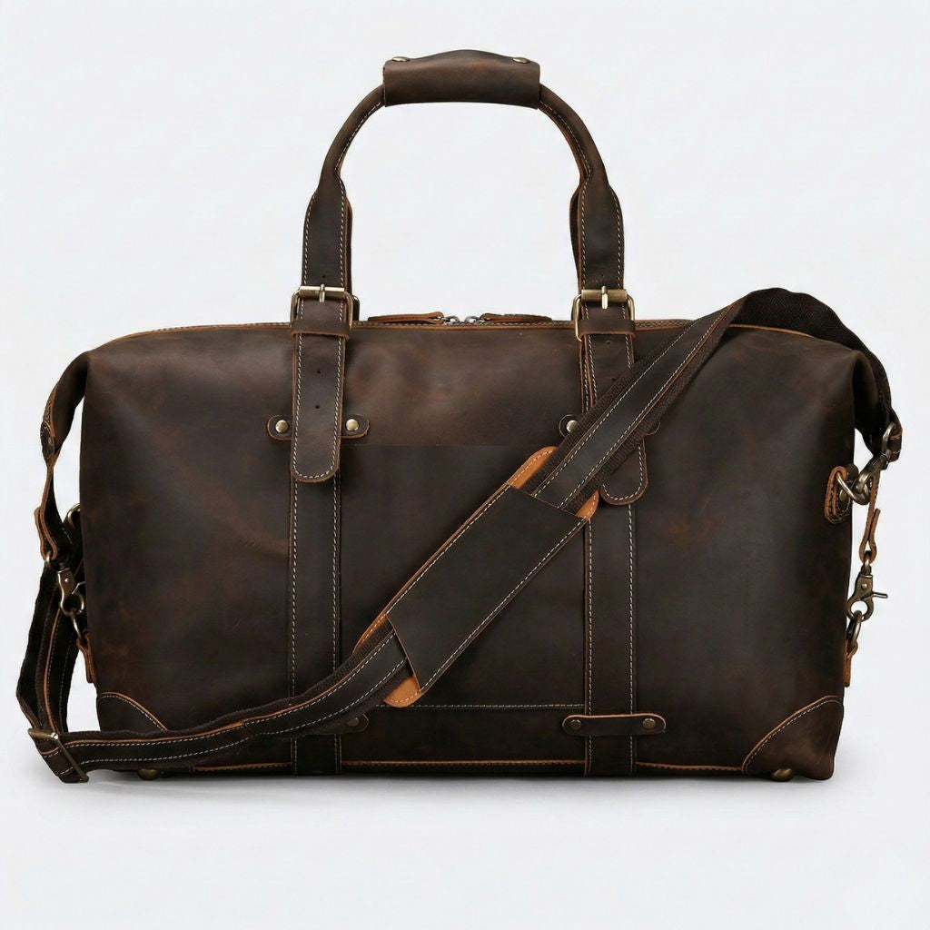 Face avant du sac de voyage cuir marron foncé patiné, poche plate avec liseré cognac et bandoulière croisée