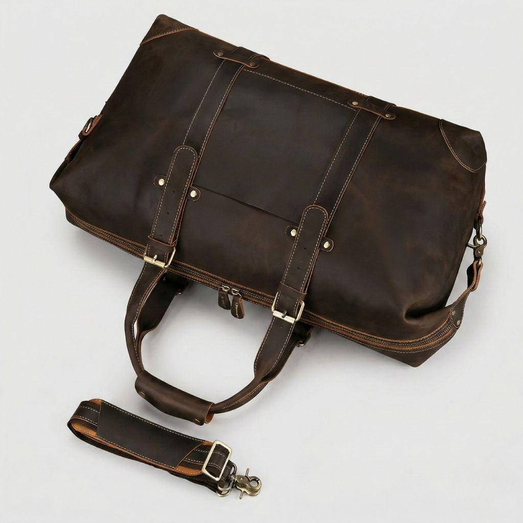 Vue plongeante du sac de voyage cuir marron chocolat, dessus et poche frontale visibles, bandoulière dépliée
