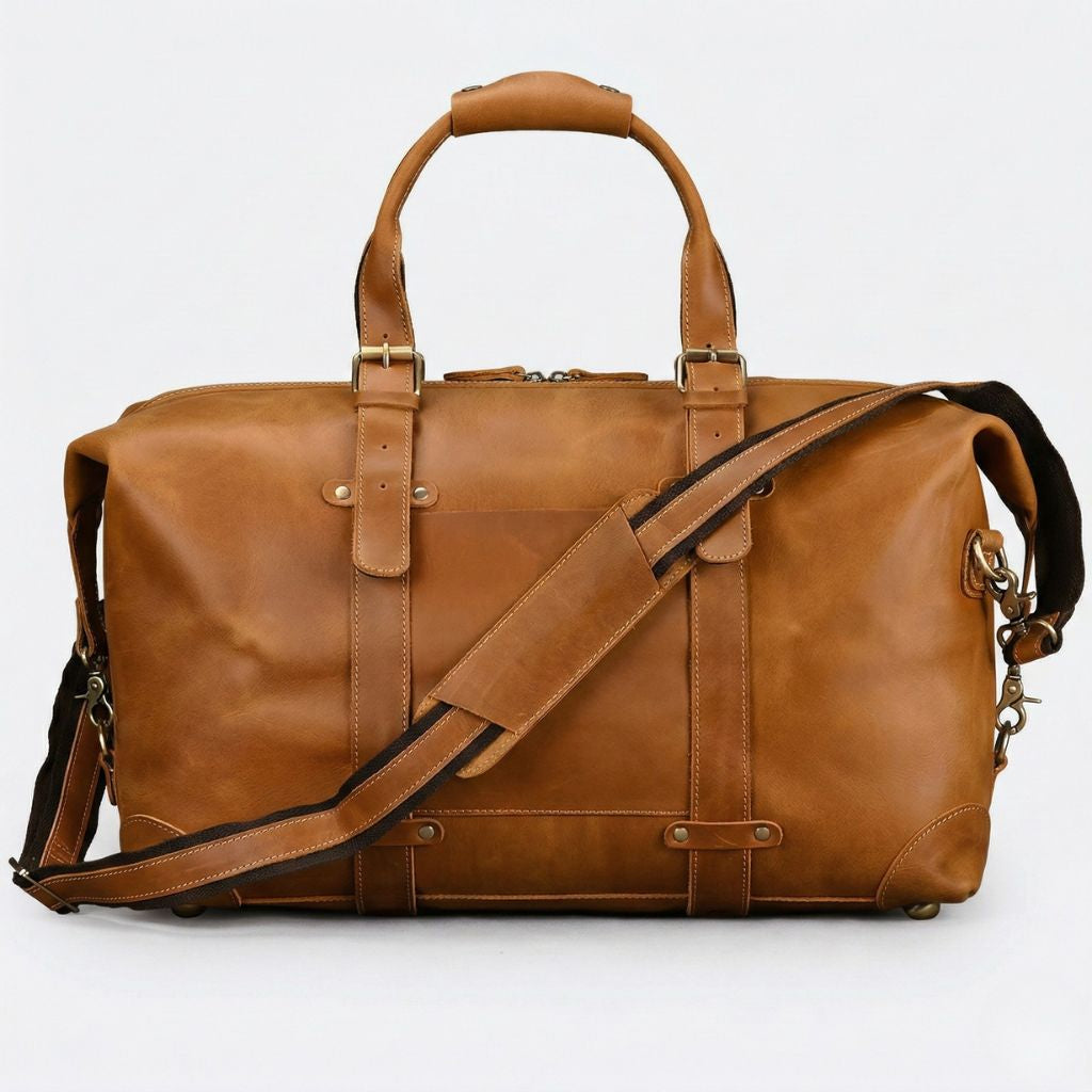 Grand sac de voyage cuir cognac, face avant avec poche glissante, deux sangles à boucles et bandoulière canvas