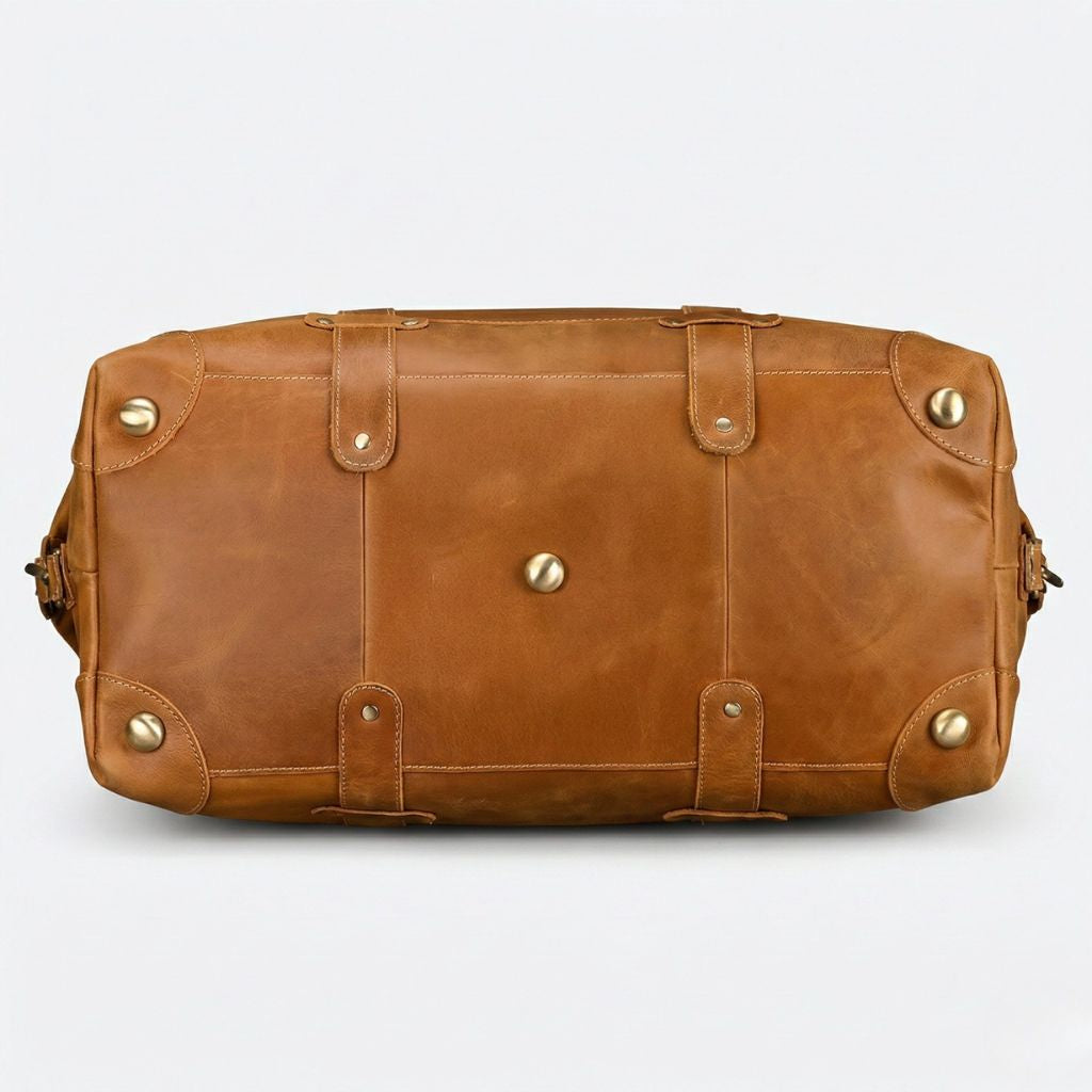Fond du sac de voyage en cuir cognac, cinq pieds protecteurs en laiton doré et coutures croisées renforcées Image