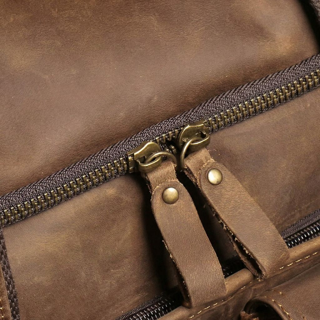 Double tirette en bronze sur la fermeture principale du sac de voyage cabine cuir, passants rivetés marron Image