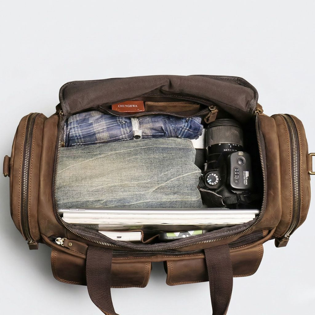 Intérieur du sac de voyage cabine cuir avec vêtements, reflex photo, ordinateur portable et carnet rangés Image