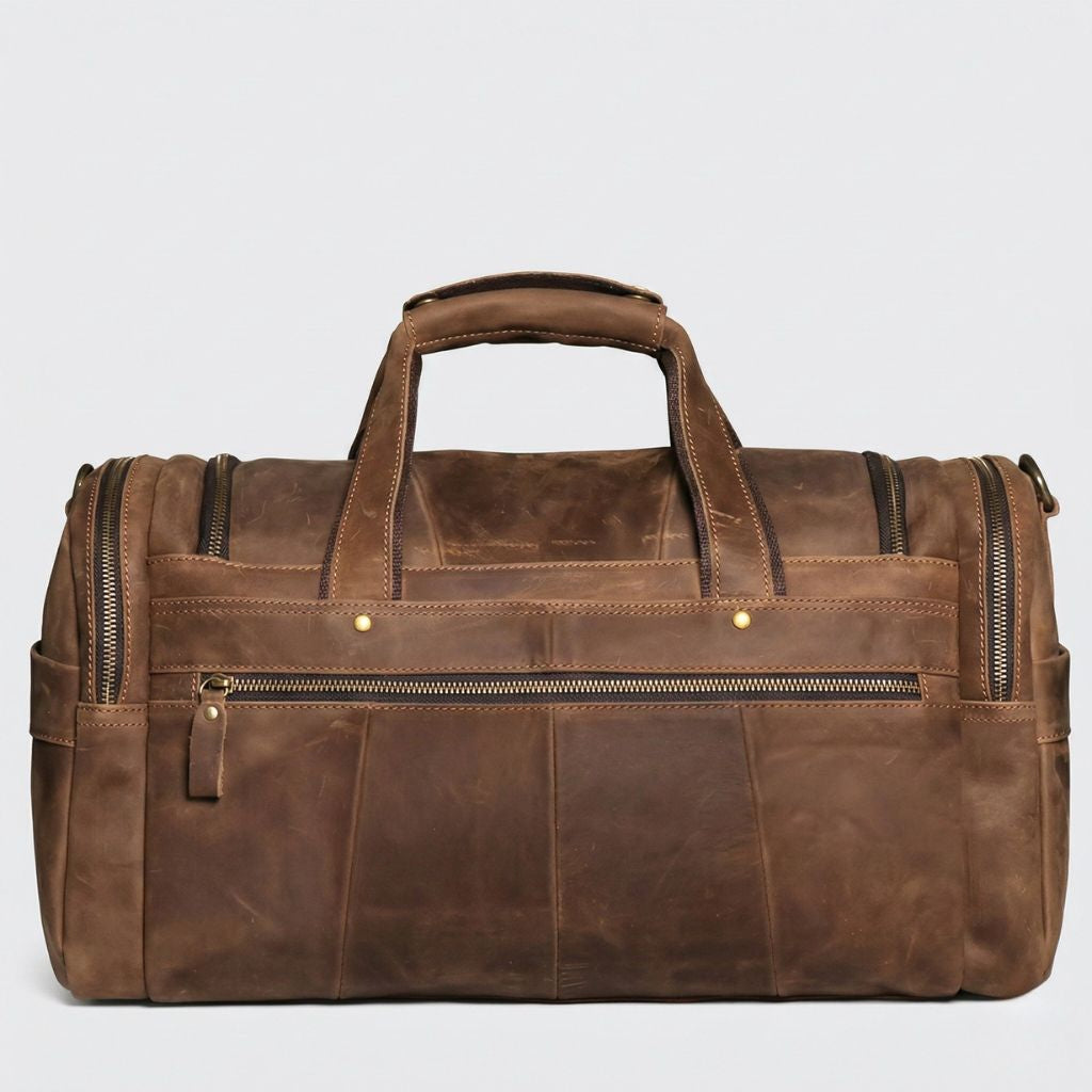 Face arrière du sac de voyage cabine cuir marron, grande poche zippée pleine largeur avec deux rivets bronze