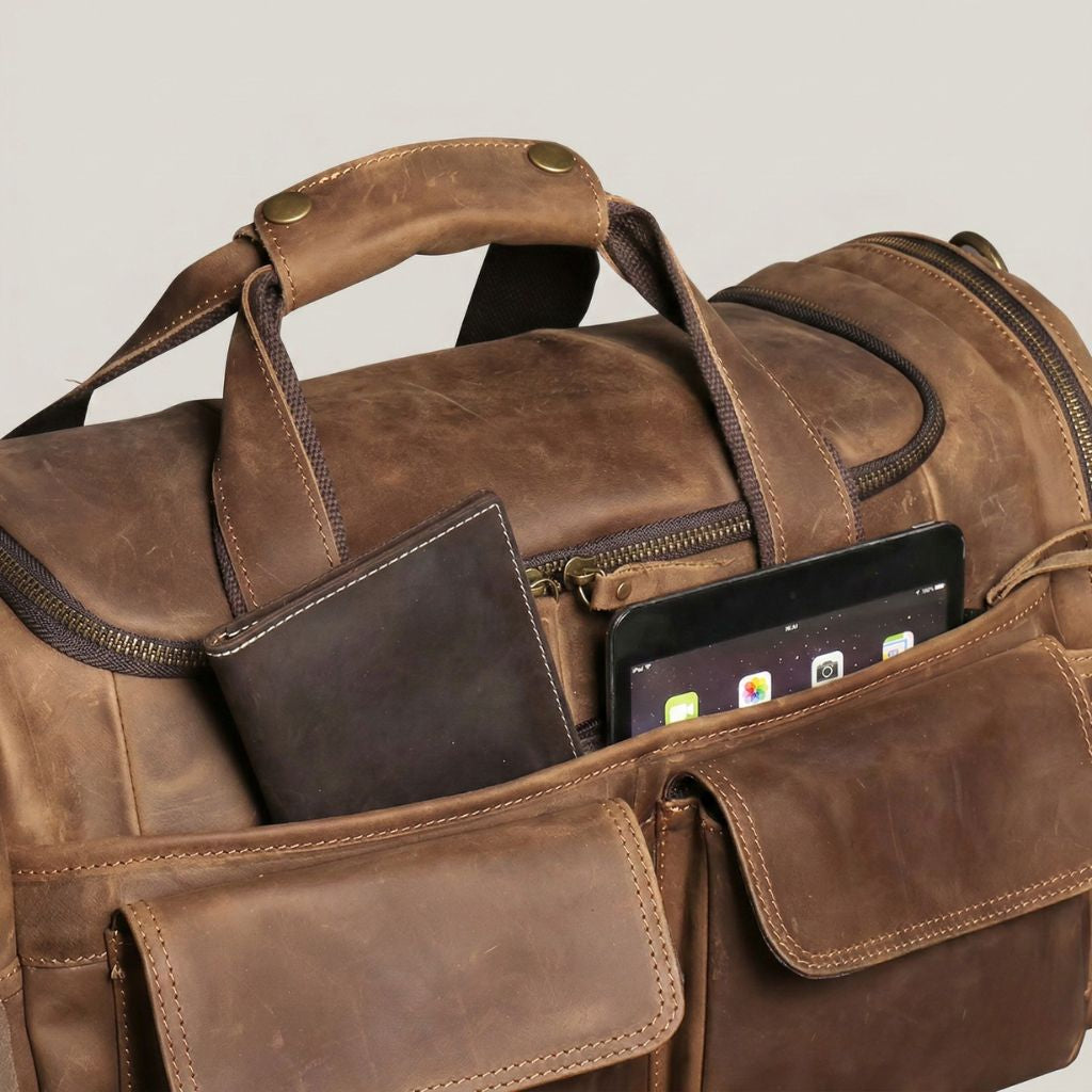 Poche supérieure zippée du sac de voyage cabine avec agenda en cuir brun et tablette noire rangés dedans