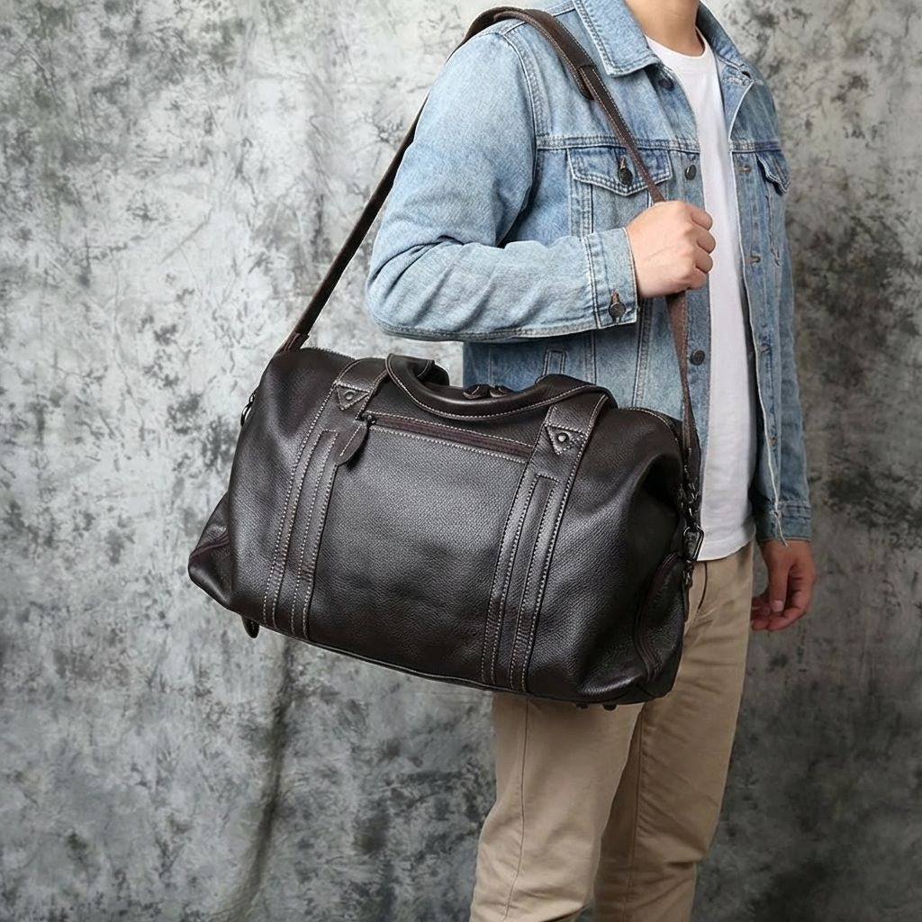 Homme en veste en jean portant un sac de voyage en cuir noir en bandoulière, style business week-end décontracté Image