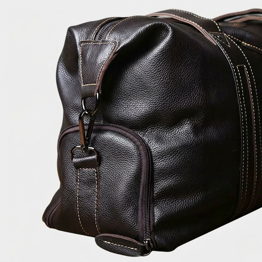 Détail de la poche latérale zippée et de l'anneau d'attache de la bandoulière en cuir marron foncé