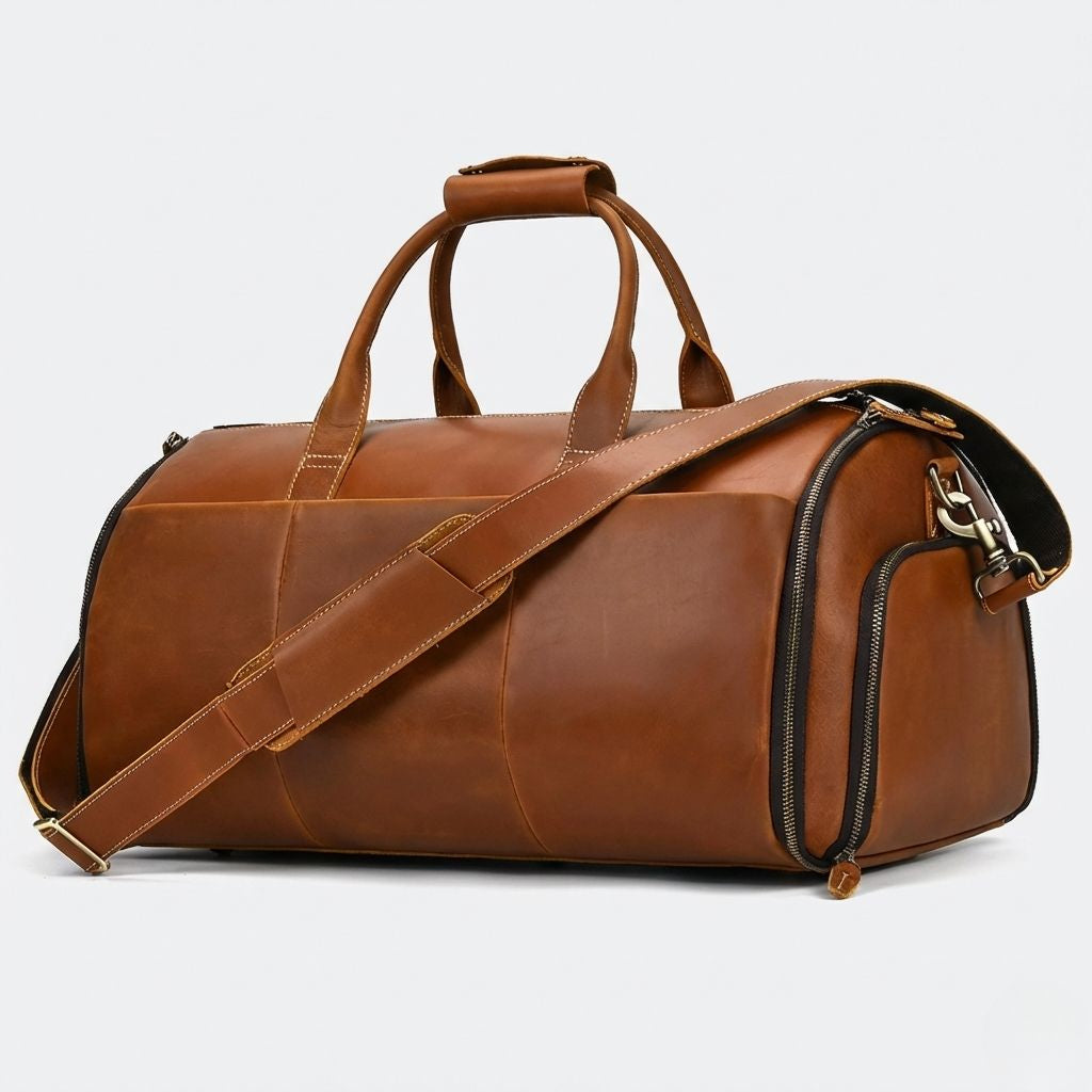 Sac de voyage cabine en cuir cognac caramel, vue 3/4 avec poignées doubles et bandoulière incluse