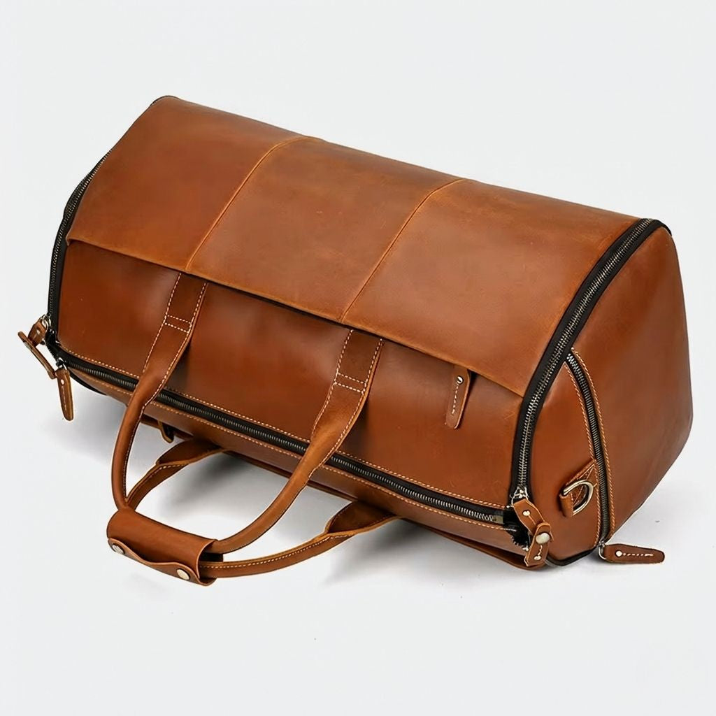 Sac de voyage cuir cognac posé de côté, zip périmétrique apparent et anneau D en laiton antique