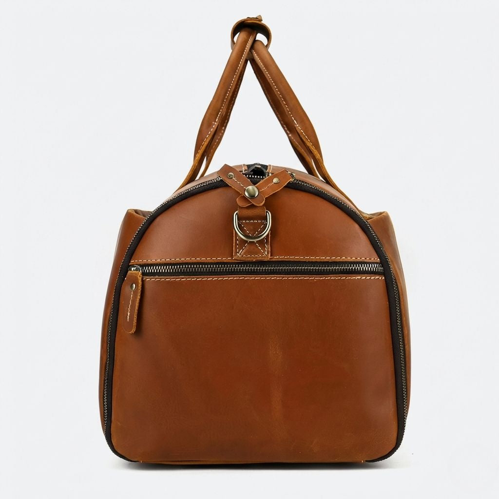 Côté du sac de voyage cuir cognac avec poche demi-lune zippée et anneau D laiton pour bandoulière