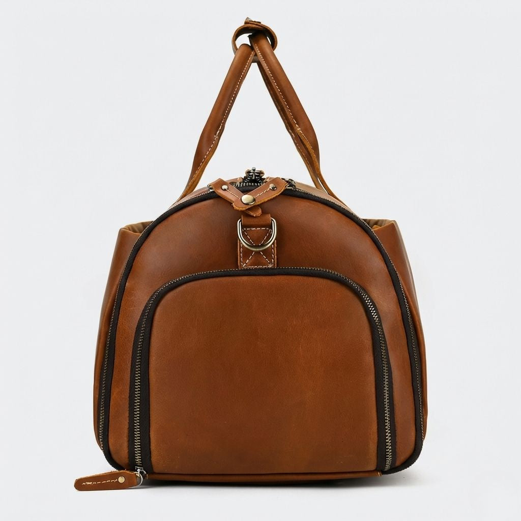 Extrémité du sac de voyage cuir cognac, poche zippée semi-circulaire et languette de zip en cuir