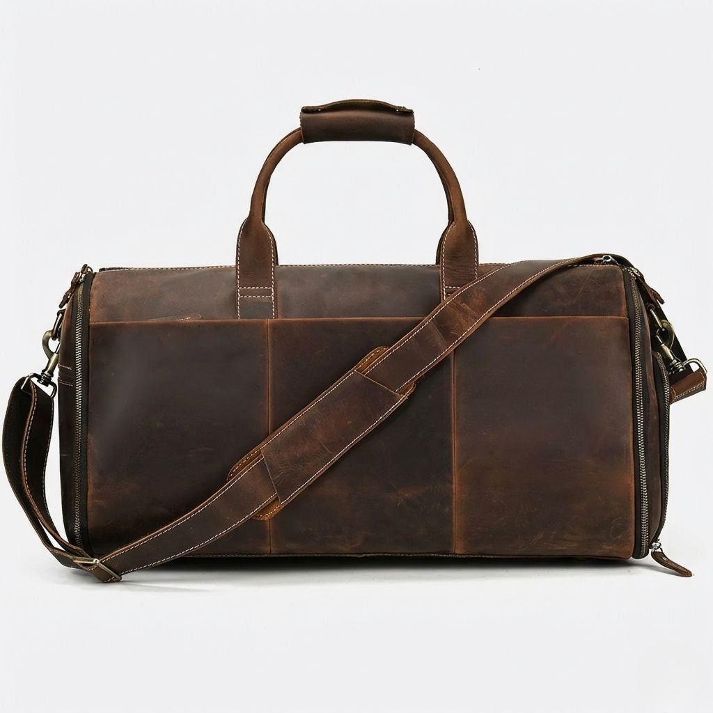 Face avant du sac de voyage en cuir brun chocolat, construction multi-panneaux et zips latéraux