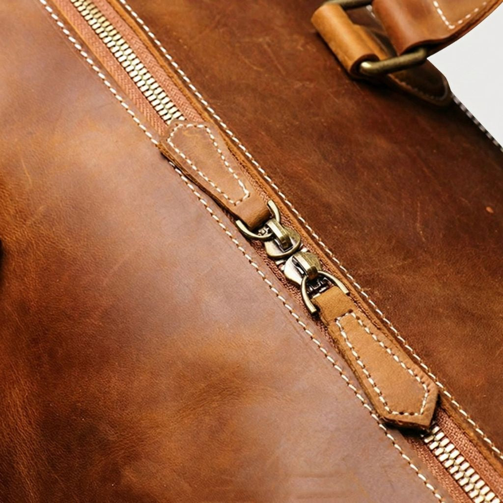 Gros plan des coutures et fermeture éclair en cuir cognac d'un sac de voyage, finition artisanale soignée Image