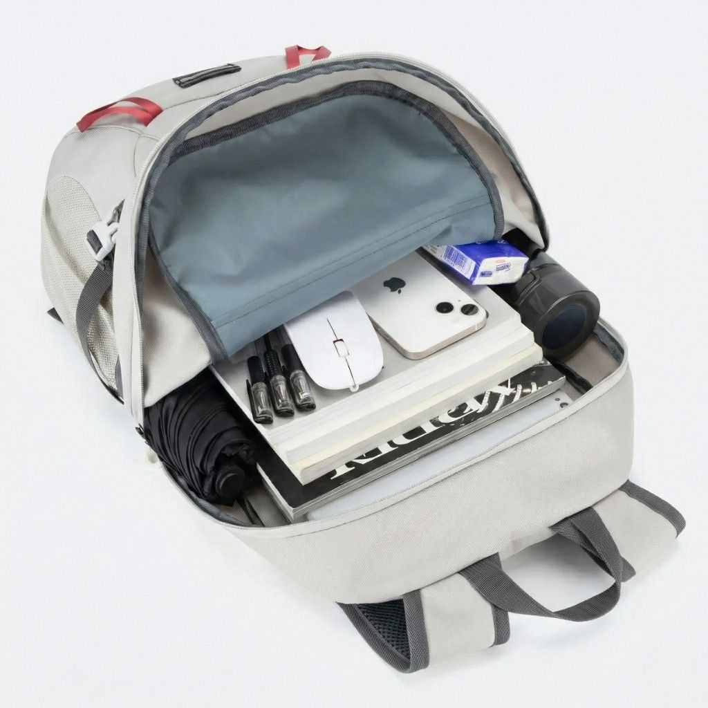 Intérieur du sac à dos de randonnée pliable gris ouvert avec ordinateur, livres, téléphone et parapluie Image