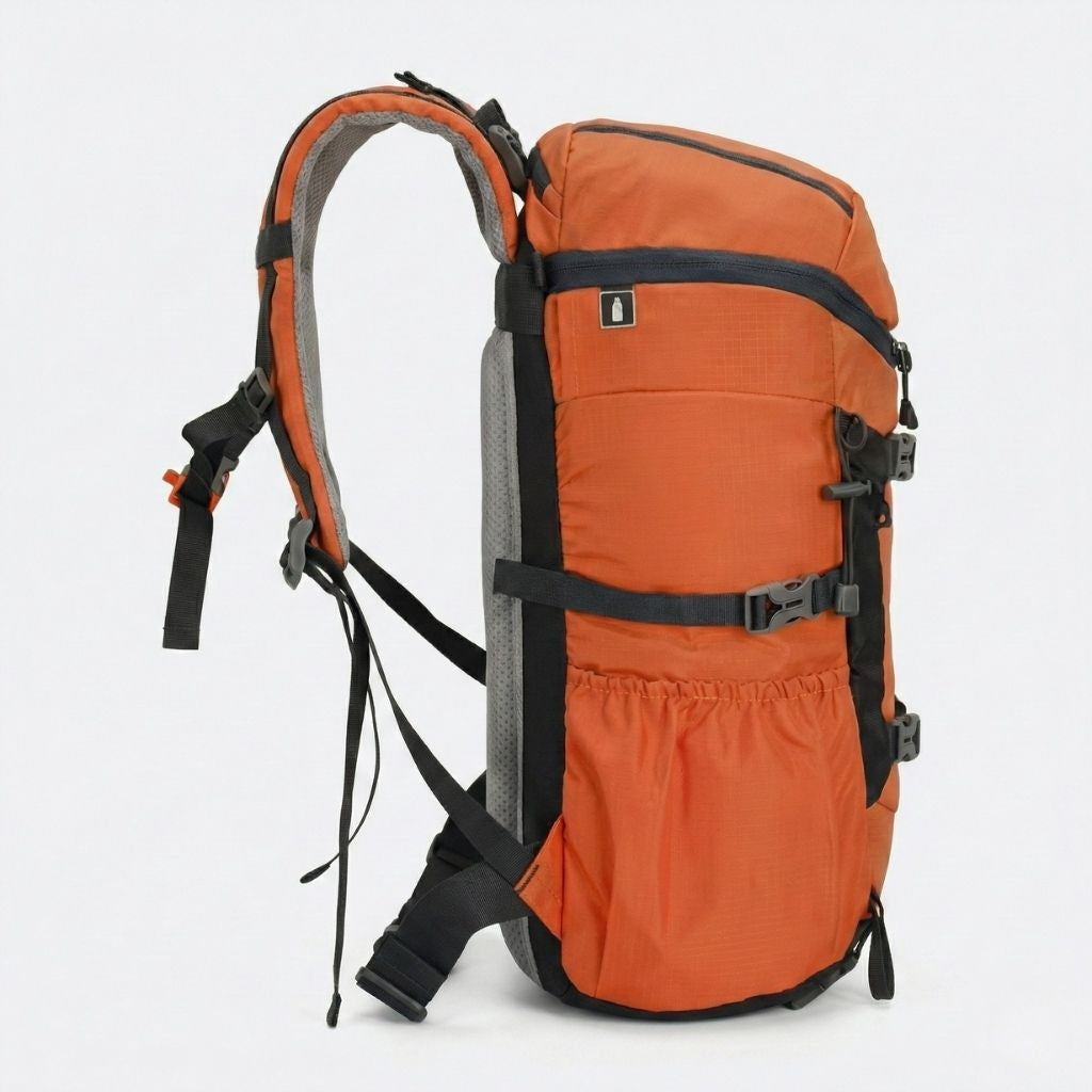 Vue de côté d'un sac à dos randonnée orange et noir compatible poche à eau, poche filet et sangles de compression.
