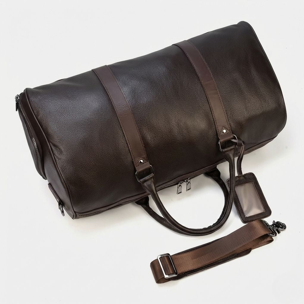 Sac de voyage cuir marron chocolat vu du dessus avec bandoulière et étiquette posées à côté