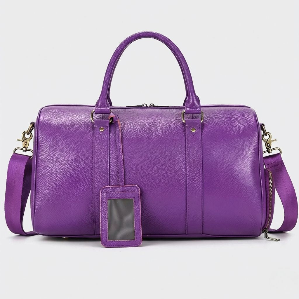 Face du sac cabine violet en cuir grainé avec étiquette porte-adresse et bandoulière assortie