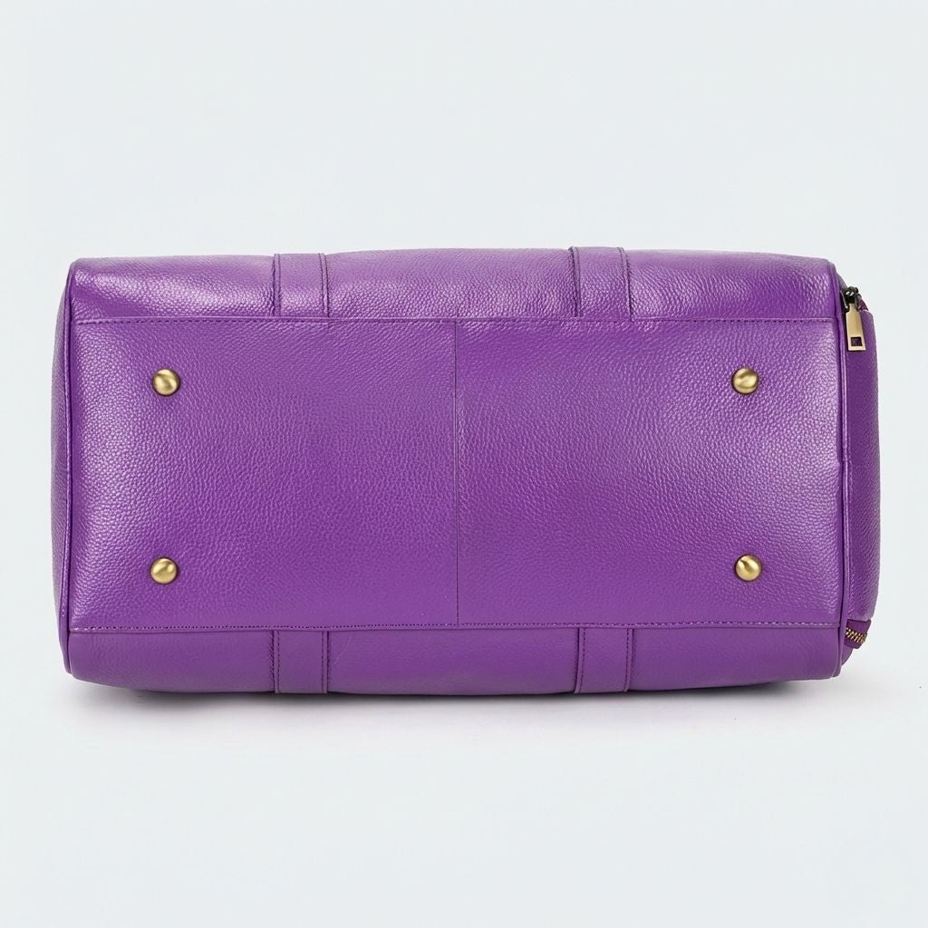 Dessous du sac cabine violet en cuir grainé avec quatre pieds protecteurs dorés bien visibles