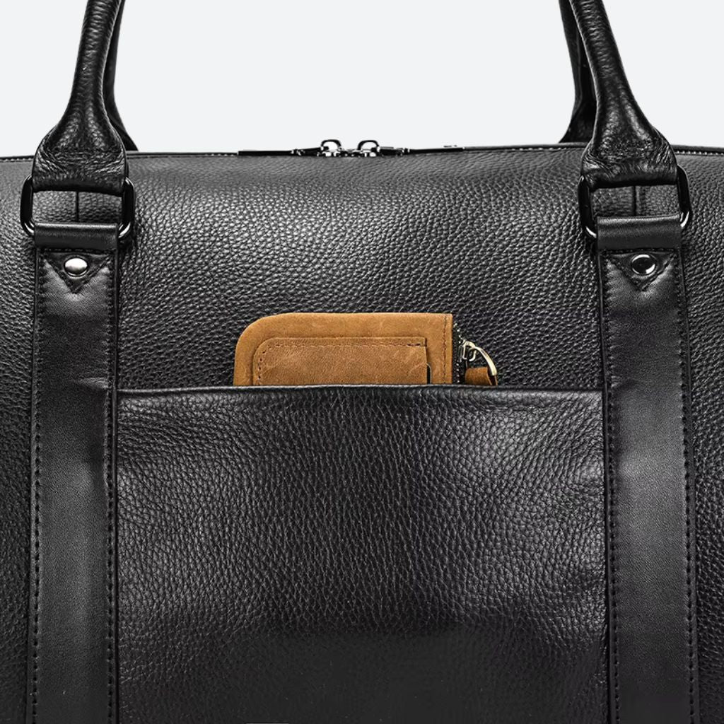 Gros plan de la poche extérieure du sac de voyage cuir grainé noir, portefeuille caramel inséré visible