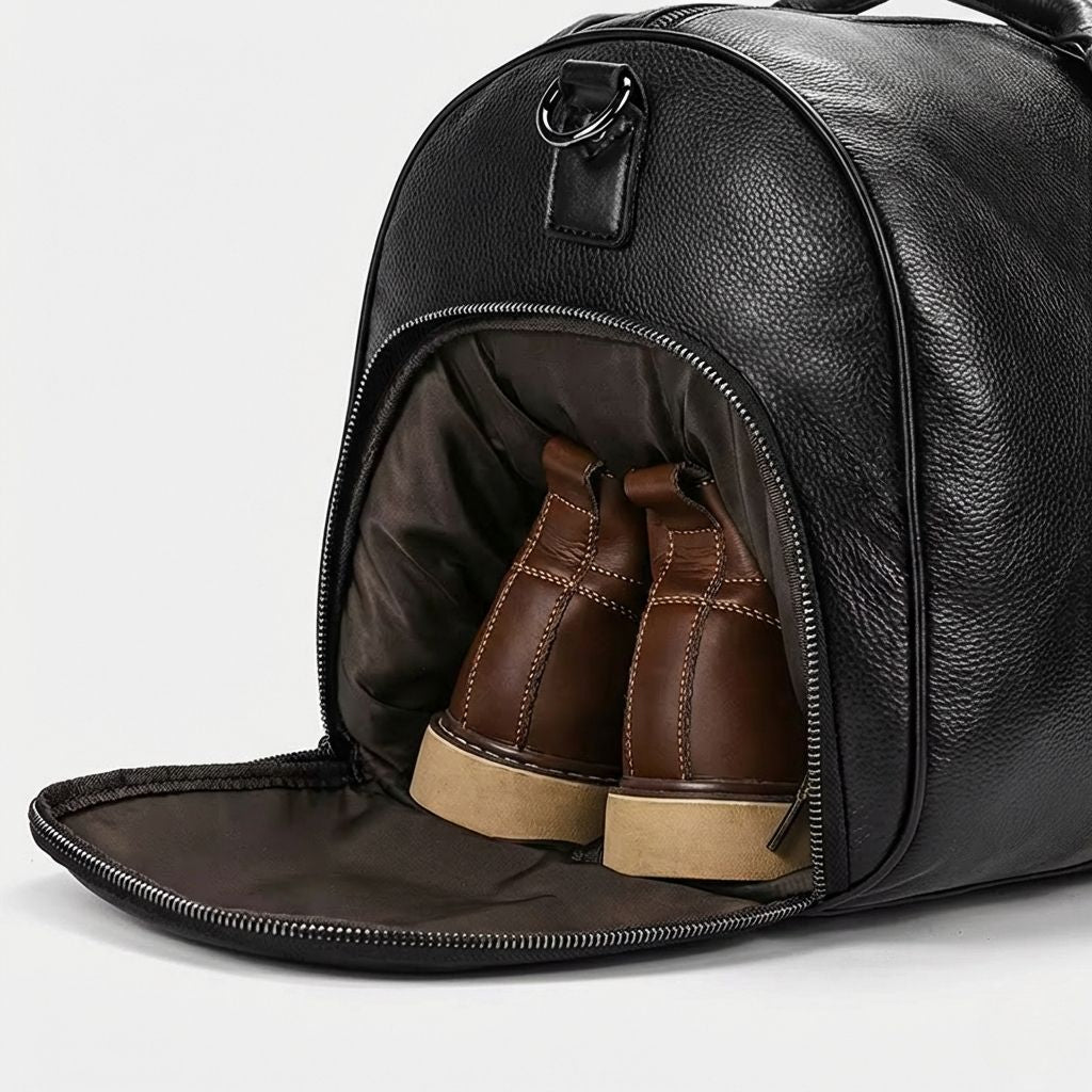 Poche chaussures d'un sac de voyage en cuir grainé noir ouverte, révélant une paire de chaussures en cuir marron Image