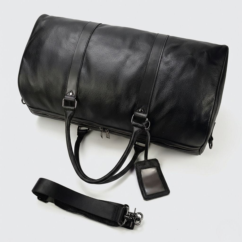 Sac de voyage cuir grainé noir couché, bandoulière détachée et étiquette de bagage à fenêtre visible