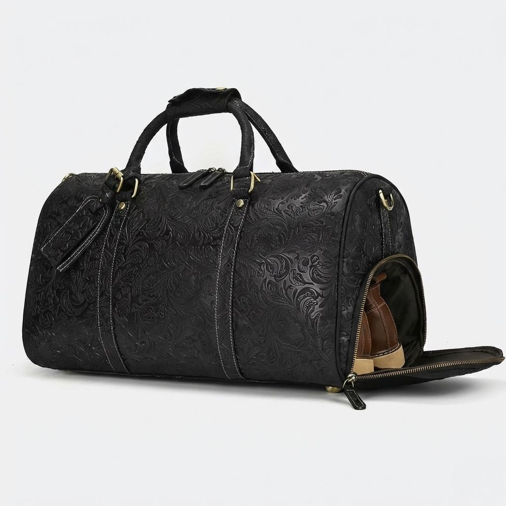 Sac de voyage cuir noir embossé motifs floraux, vue 3/4 face avec bandoulière et coutures blanches contrastées
