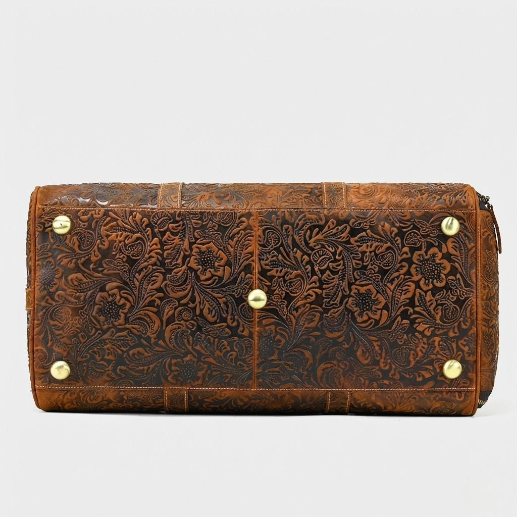 Dessous du sac de voyage cuir brun embossé, quatre pieds protecteurs dorés et coutures solides apparentes