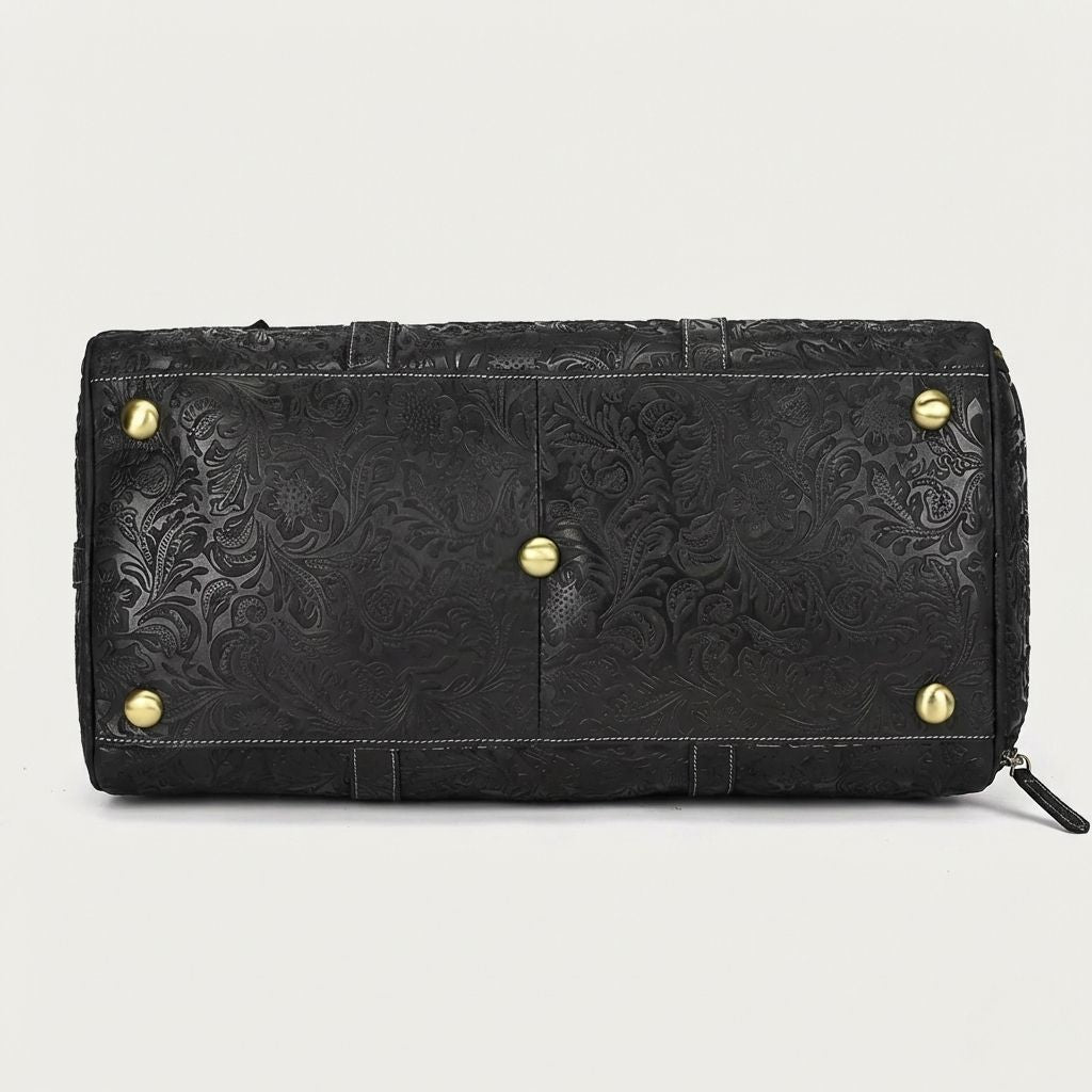 Dessous du sac de voyage cuir noir embossé floral, pieds protecteurs dorés et coutures blanches contrastées