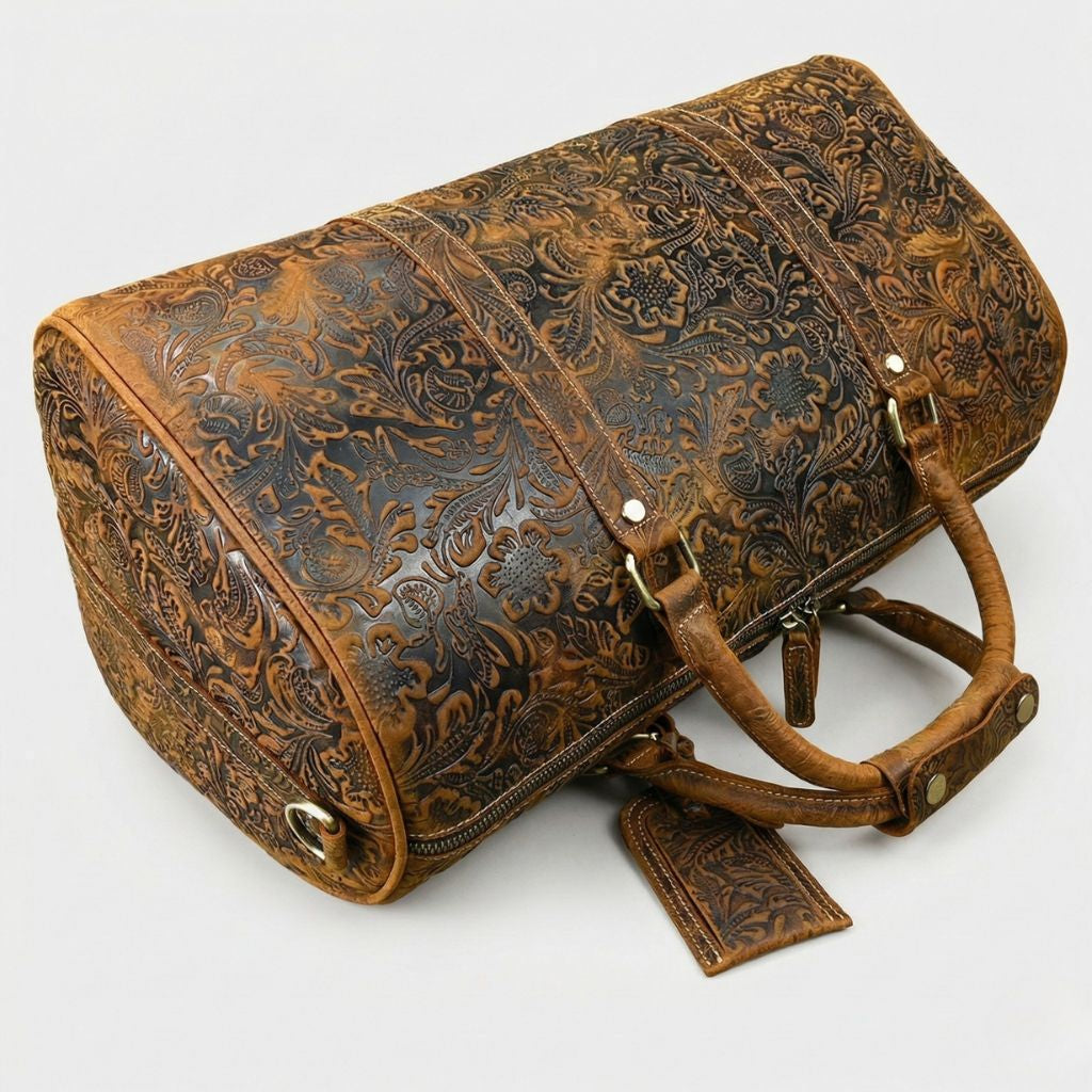 Vue du dessus du sac de voyage couché, cuir brun embossé floral, poignées et étiquette bagage apparentes