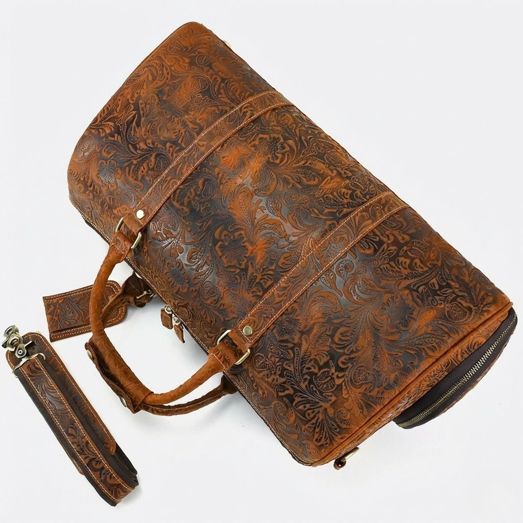 Sac de voyage cuir brun embossé floral posé de côté, vue des poignées et de la bandoulière amovible en cuir