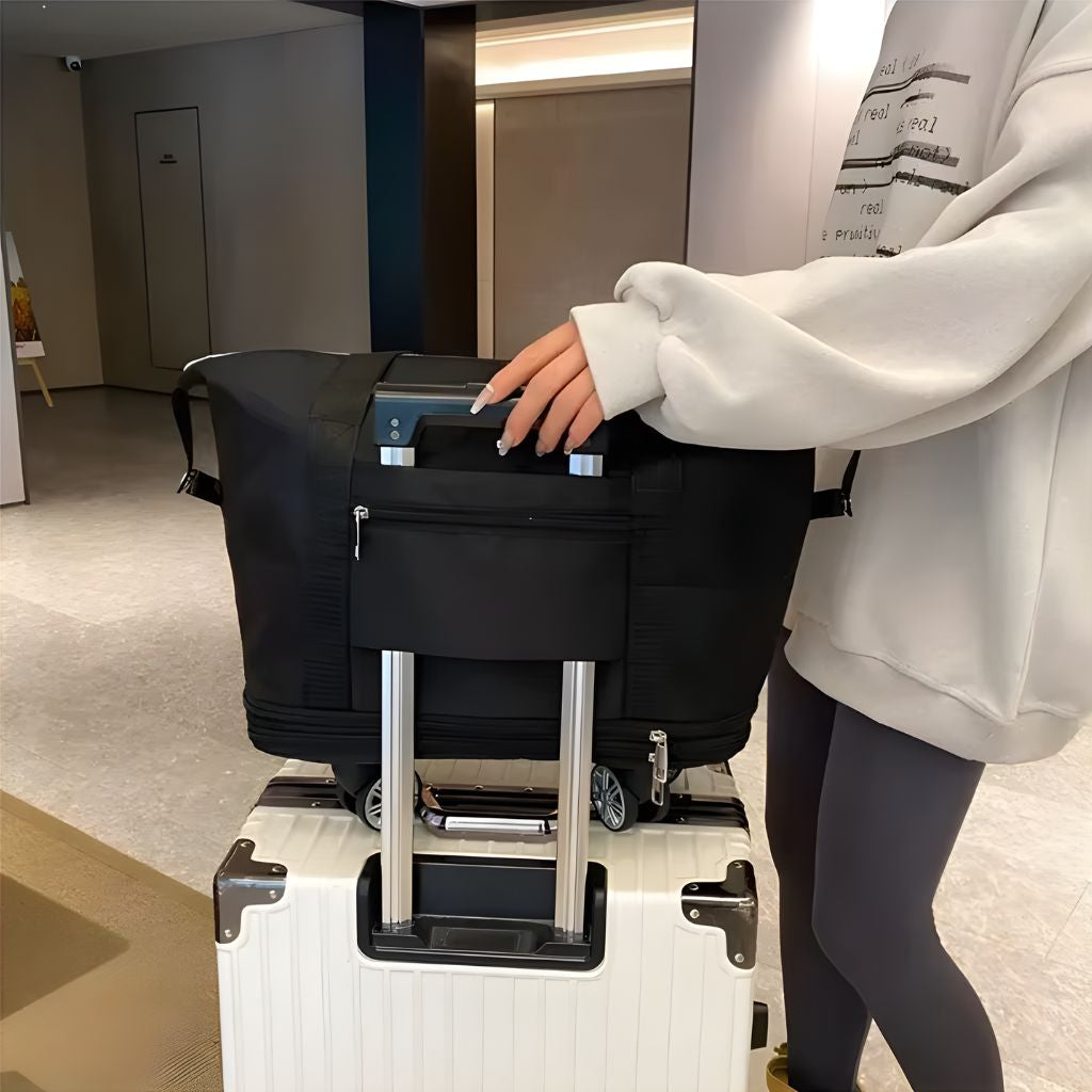 Femme posant son sac de voyage noir extensible à roulettes sur une valise argentée dans un couloir d'hôtel