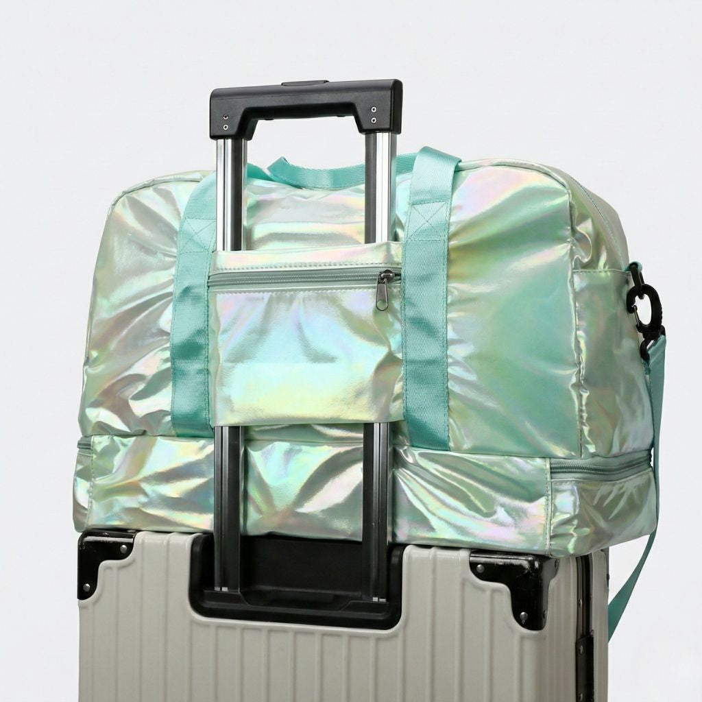 Sac de voyage holographique vert menthe irisé posé sur une valise via son système de passage trolley Image