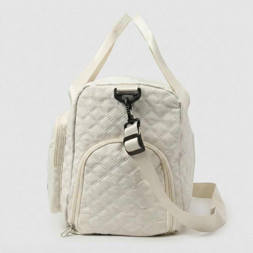 Profil droit du sac de voyage femme matelassé blanc cassé, crochet de bandoulière noir réglable et poche latérale