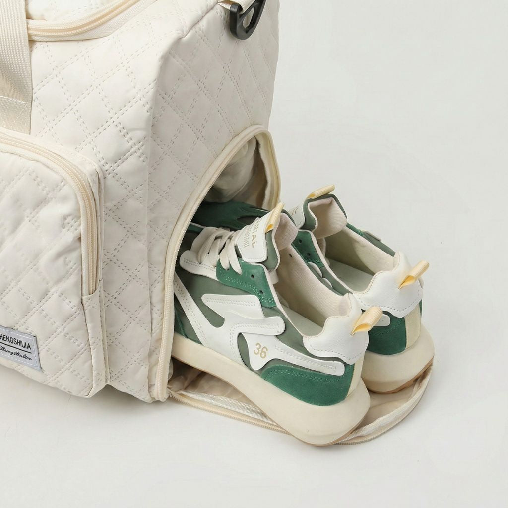 Compartiment chaussures latéral d'un sac de voyage femme matelassé blanc cassé avec des baskets vertes Image