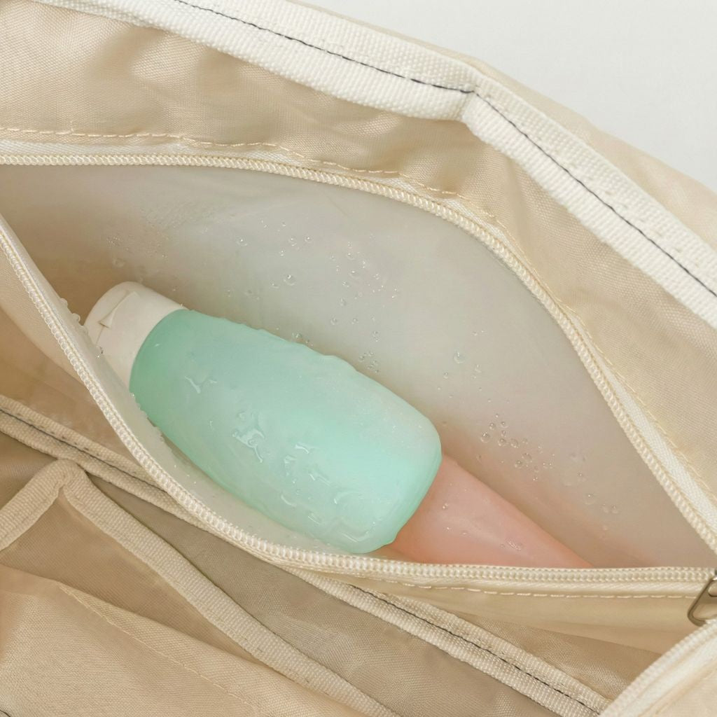 Poche intérieure imperméable d'un sac de voyage femme matelassé crème avec flacons de toilette Image