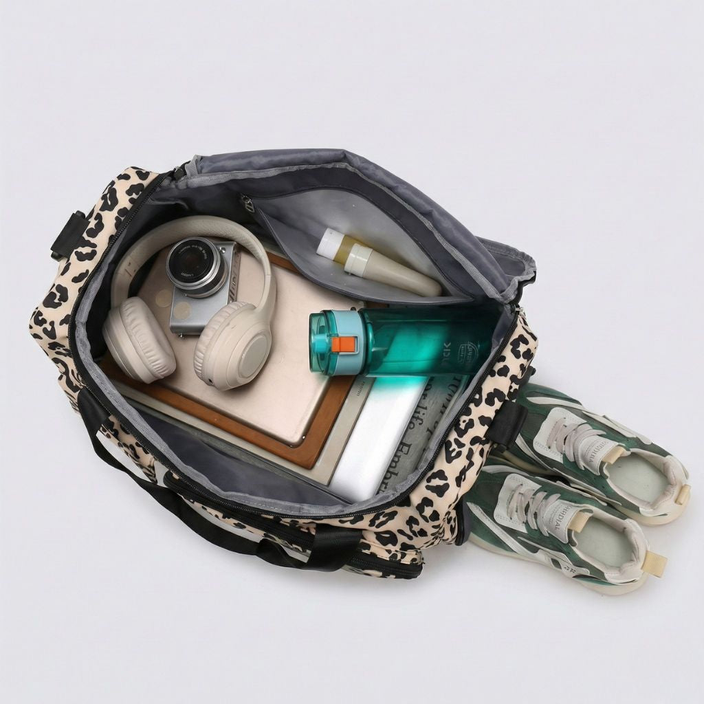 Vue du dessus d'un sac de voyage femme imprimé léopard beige ouvert, avec casque, appareil photo et chaussures Image