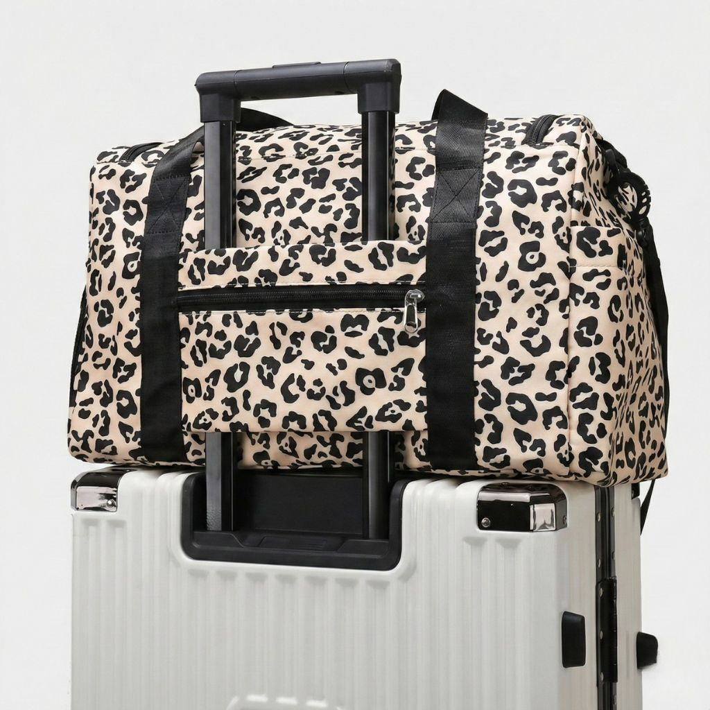 Sac de voyage femme à imprimé léopard beige posé sur une valise via le système de glisse trolley Image