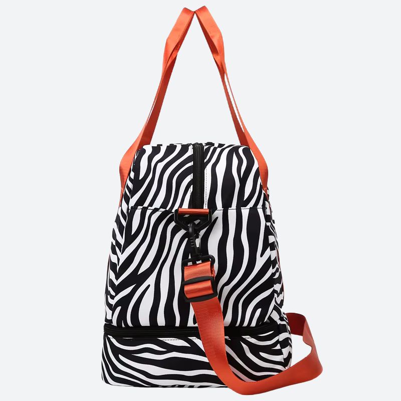 Sac de voyage femme grande capacité à motifs zèbre noir et blanc avec anses et bandoulière orange, vue de côté sur fond uni blanc gris