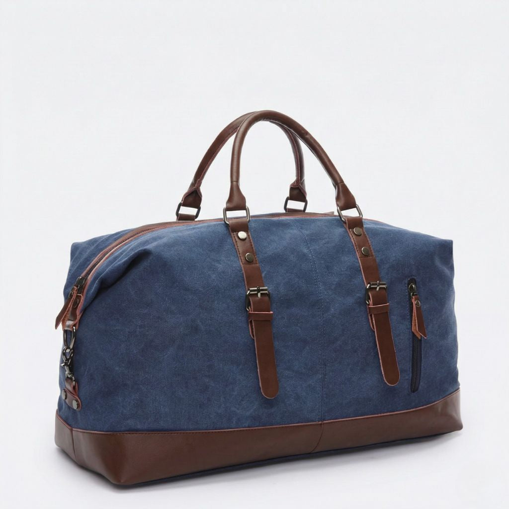 Sac de voyage toile canvas bleu marine, vue 3/4, renforts et poignées cuir brun, sangles boucles et poche zippée