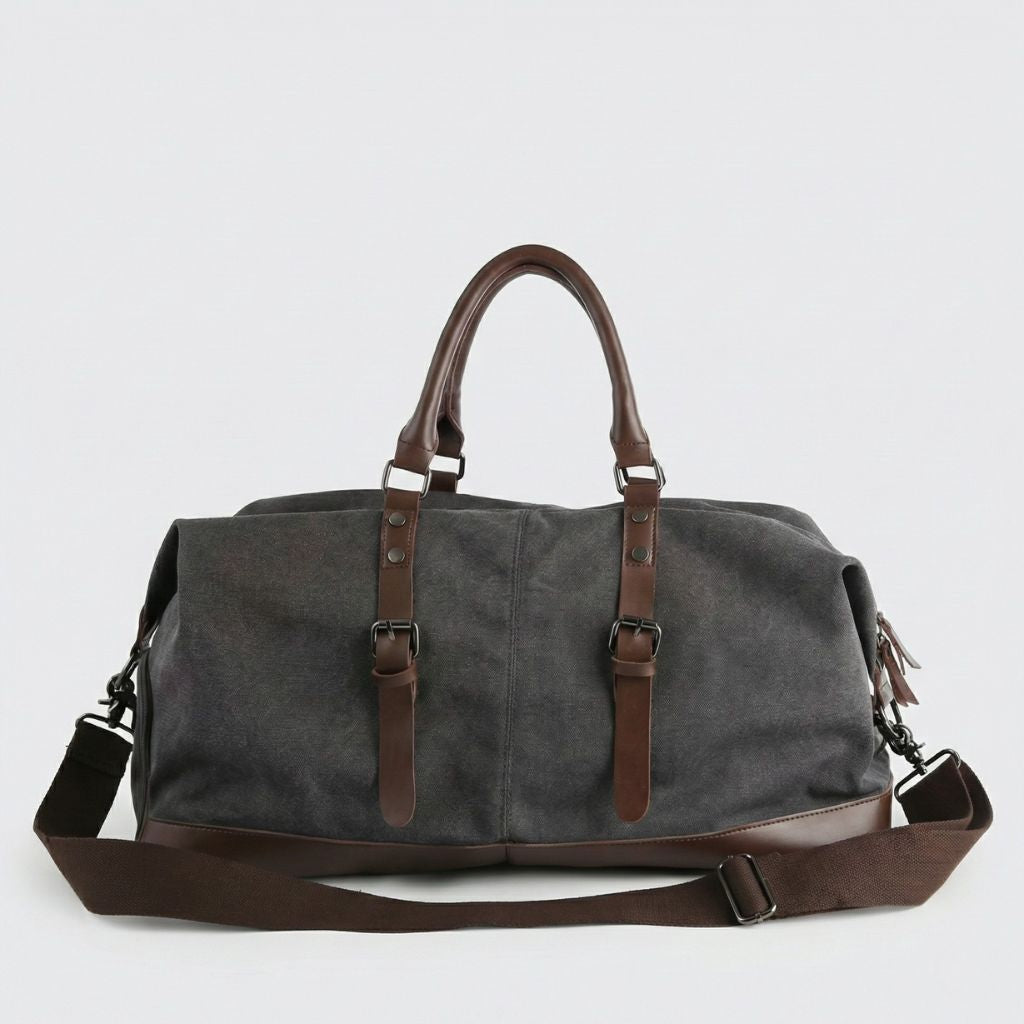 Sac de voyage toile canvas gris anthracite vu de face, poignées et bandoulière cuir brun, doubles boucles de sangle
