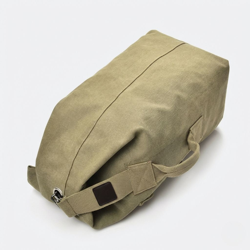 Dessous du sac de voyage en toile kaki, détail des bretelles canvas, du mousqueton métal et du fond renforcé