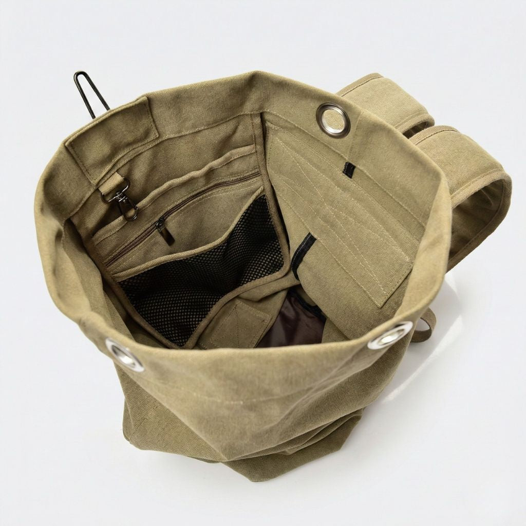 Intérieur du sac de voyage canvas ouvert, avec poches filet, pochette zippée et œillets métal visibles du dessus