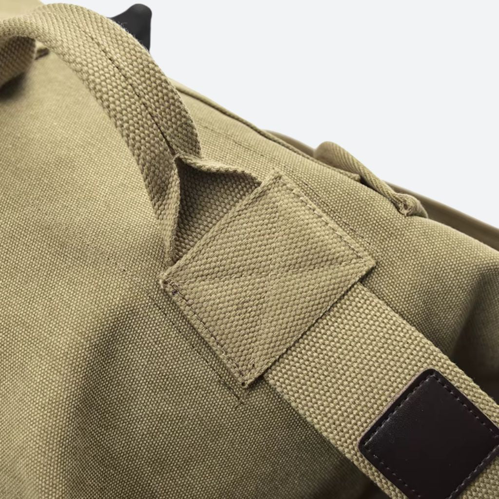 Détail de la poignée renforcée en toile canvas avec patch en cuir brun sur le sac de voyage pour homme