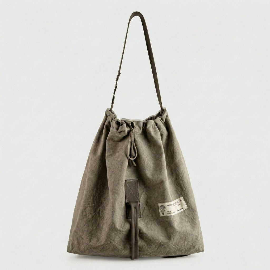 Grand sac de voyage en toile militaire kaki délavé, fermeture cordonnée, longue bandoulière et étiquette vintage