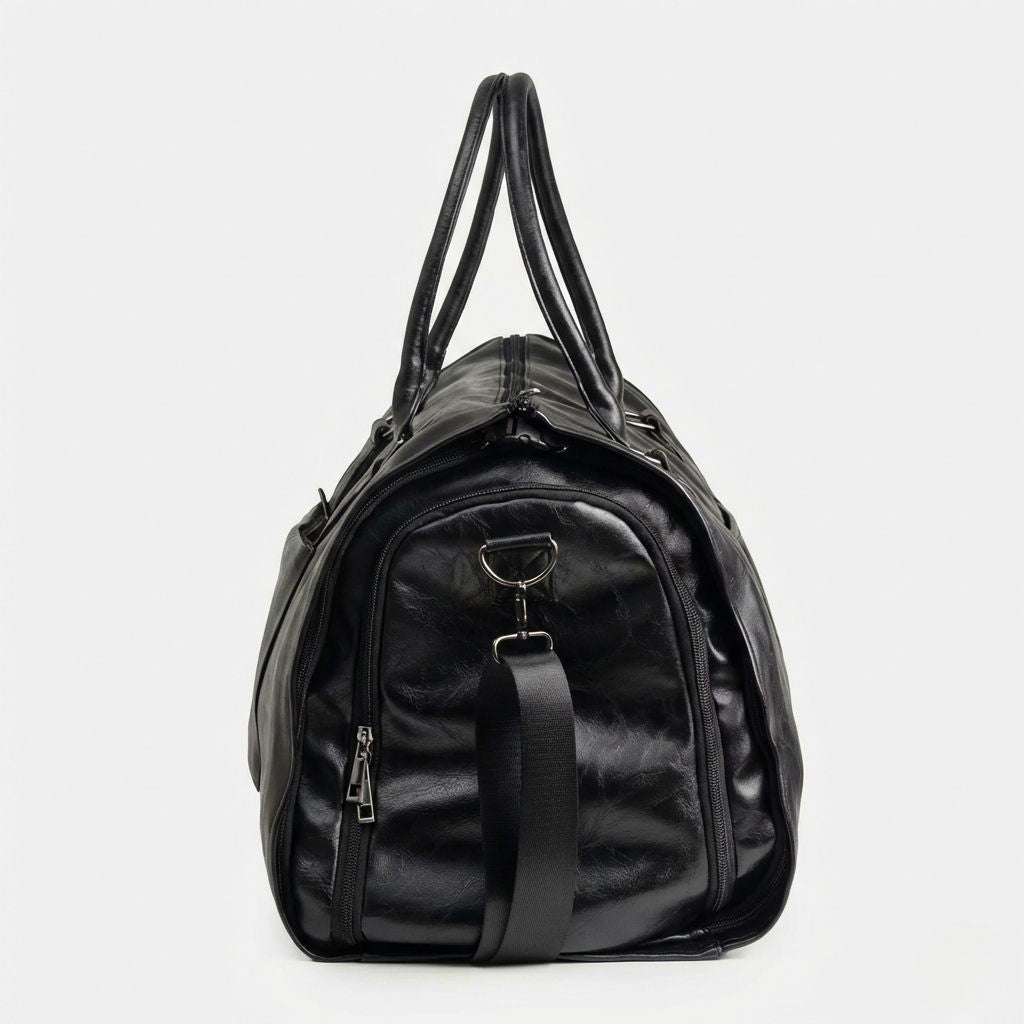 Vue latérale du sac de voyage noir montrant le grand compartiment chaussures zippé et la fixation de bandoulière