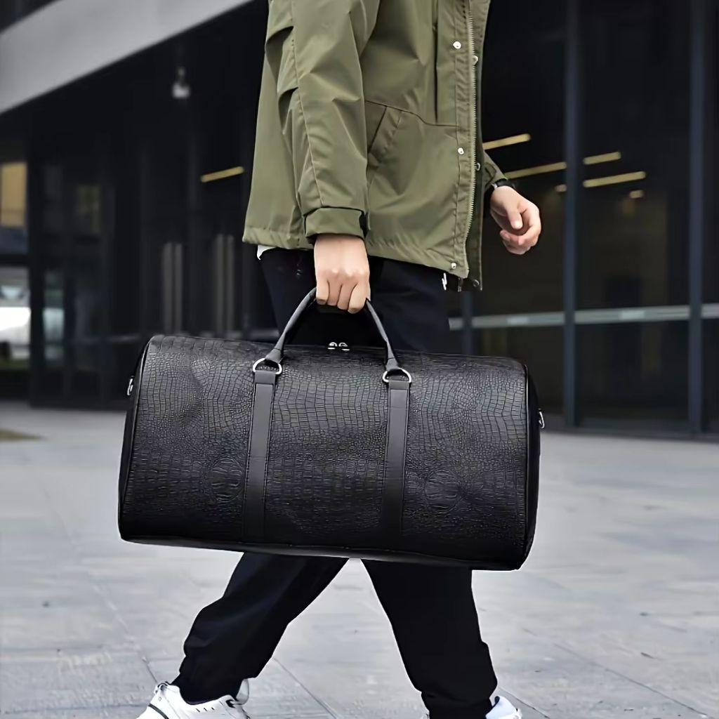Homme marchant en ville avec un sac de voyage cylindrique en simili cuir noir à motif crocodile Image