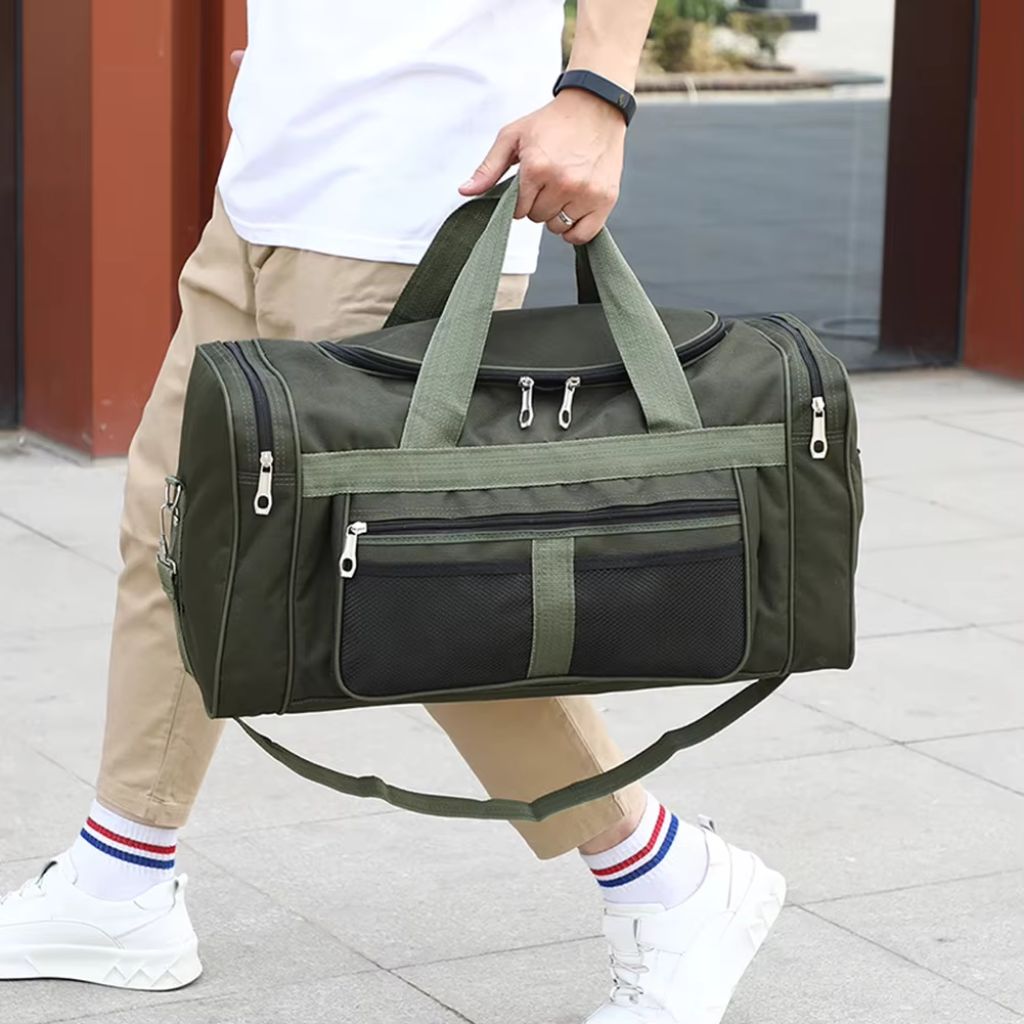 Sac de voyage homme vert kaki polochon porté à la main par un homme en ville, usage sport et voyage